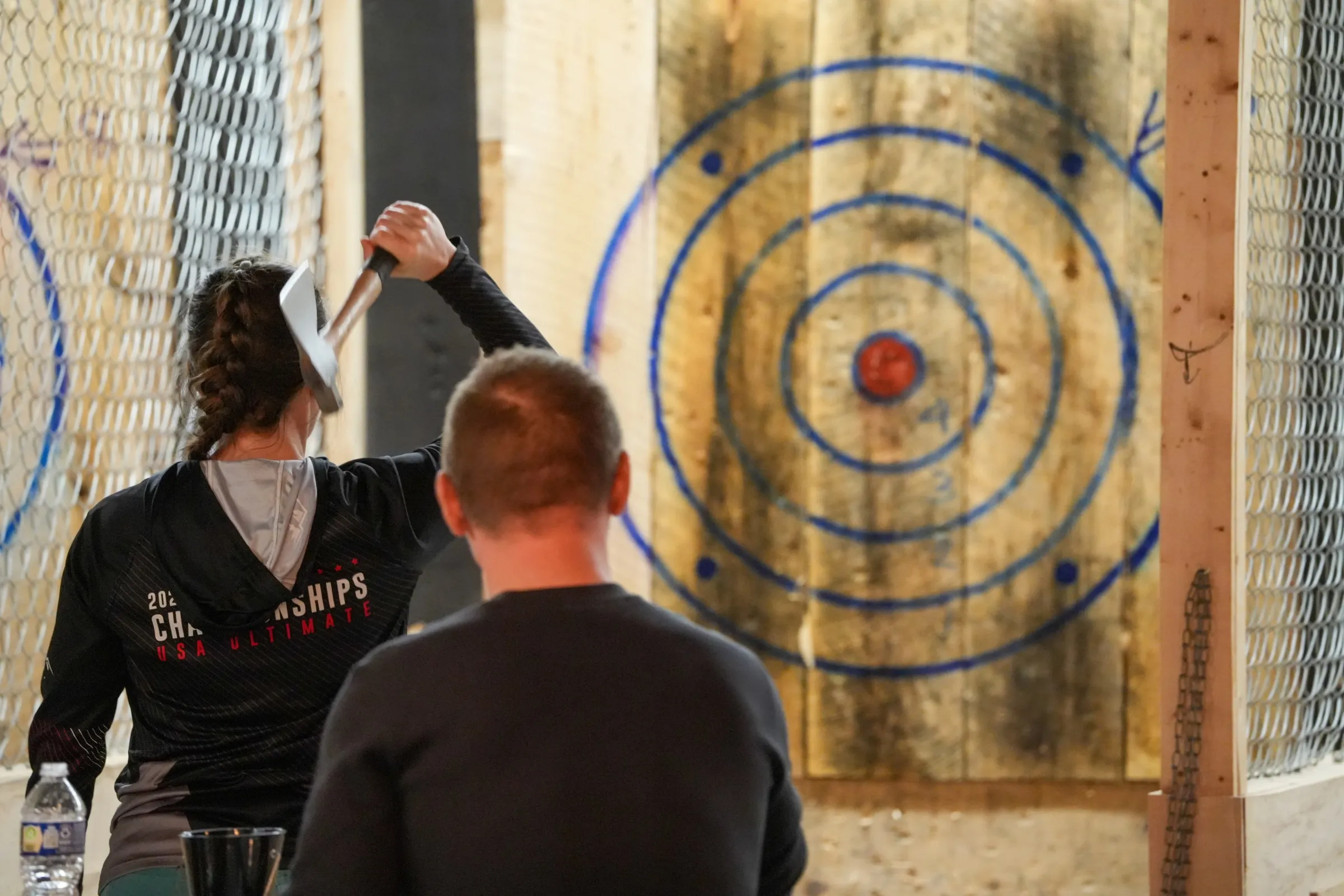 A guest preparing to throw an axe toward a wooden target